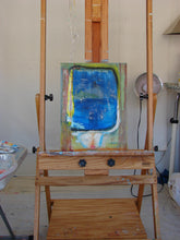 Painting on an easel with a blue abstract design in a room setting.